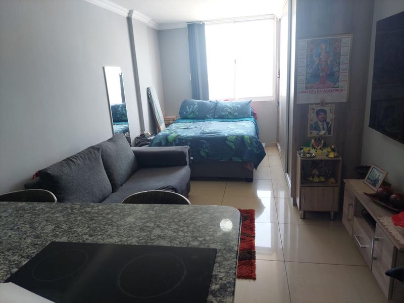 Open-plan studio apartment featuring a compact kitchen area with granite countertops, tiled flooring, and built-in wardrobe storage.