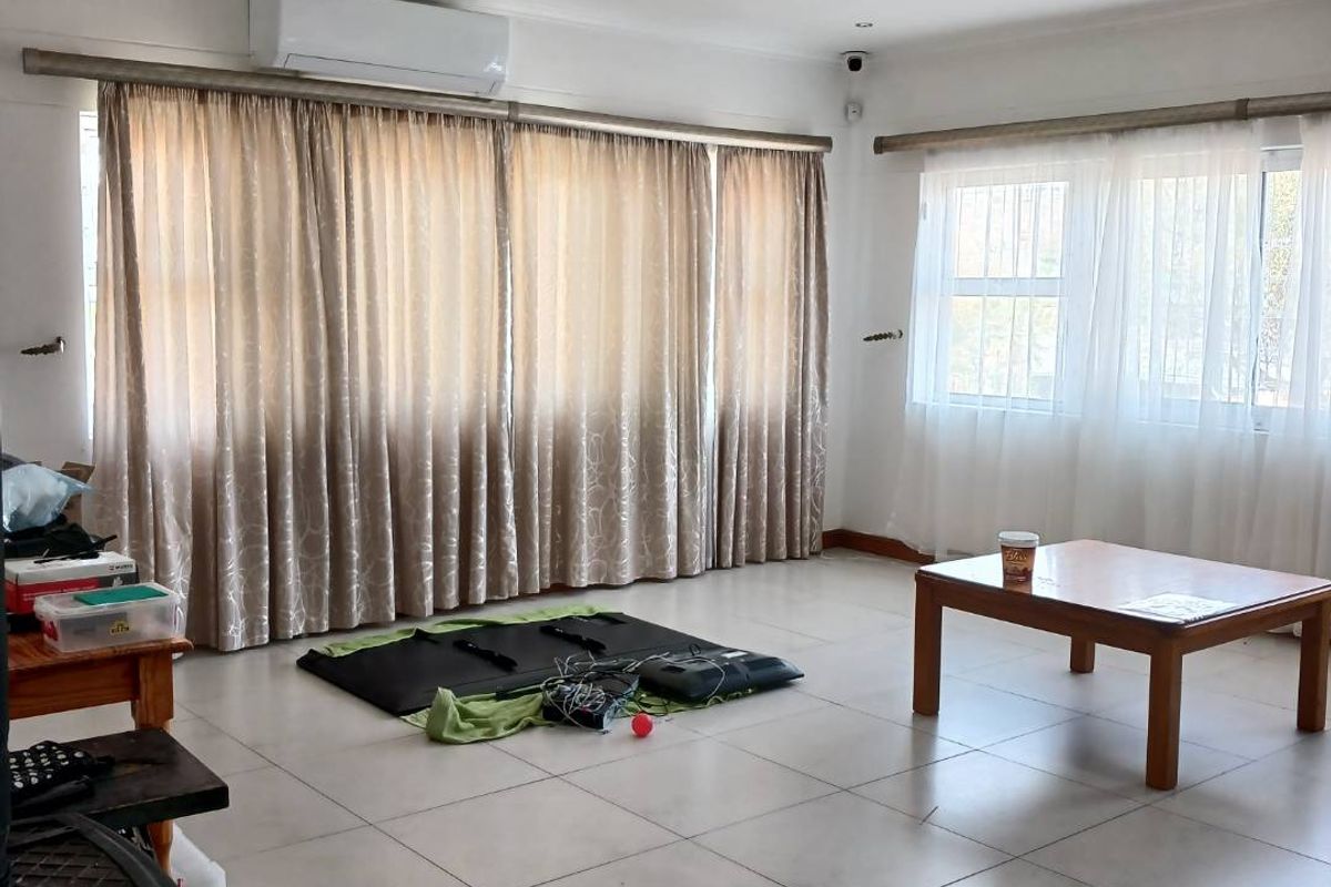 Spacious living area featuring neutral tiled flooring, recessed downlighting, and a wall-mounted air conditioning unit.
