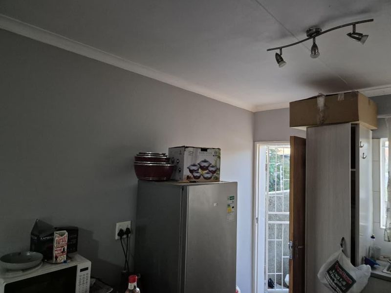A functional kitchen area featuring track lighting and access to an exterior security gate, providing a practical layout for daily use.