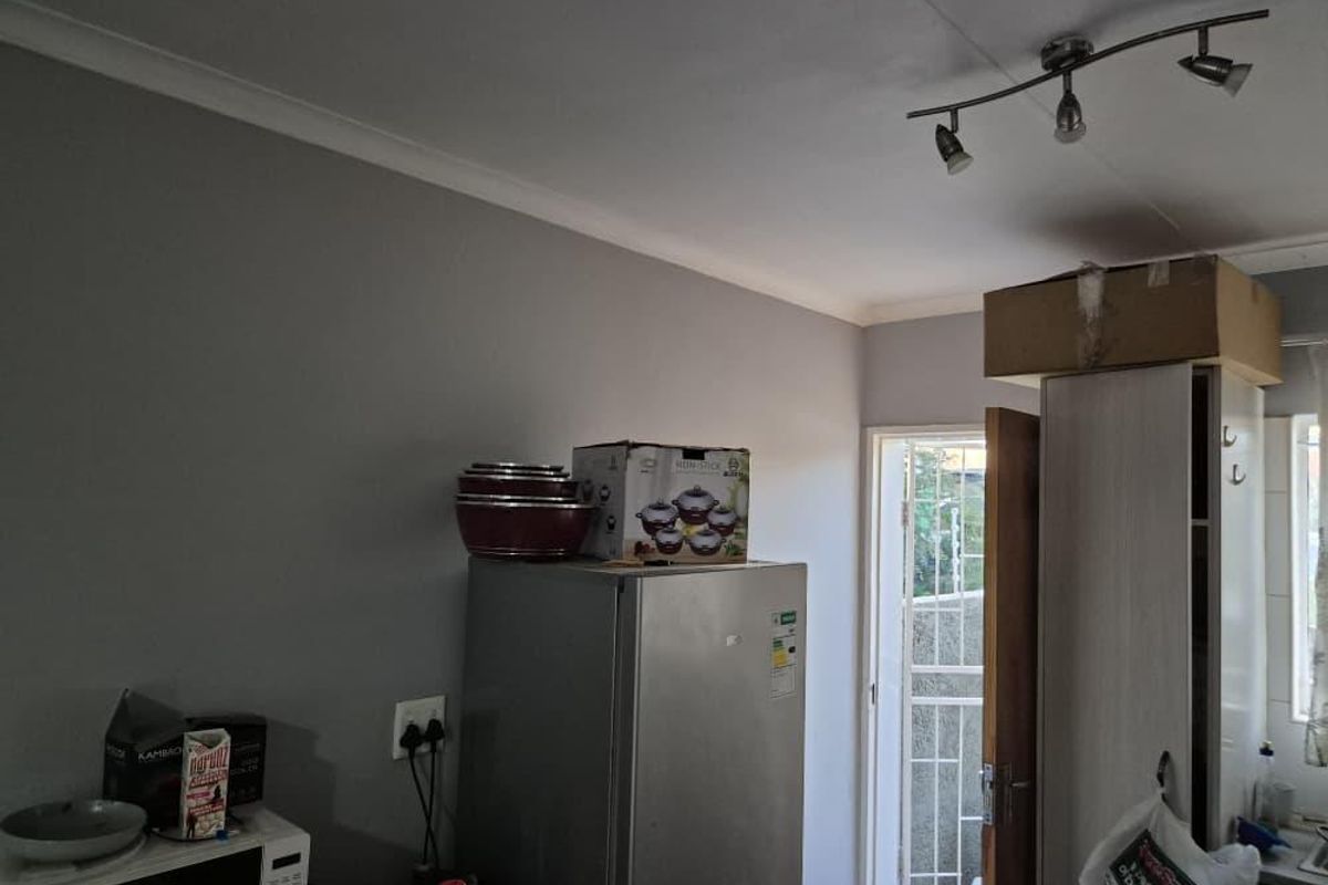 A functional kitchen area featuring track lighting and access to an exterior security gate, providing a practical layout for daily use.