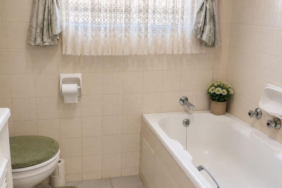 A functional bathroom featuring a built-in bathtub, wall-mounted toilet, and neutral wall tiling, offering a clean and practical space.