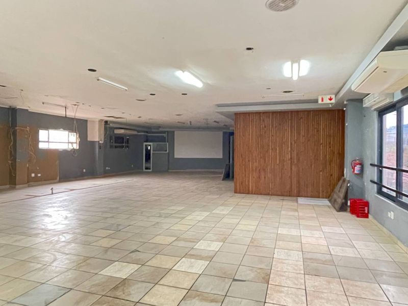 Spacious open-plan industrial area featuring tiled flooring, wood paneling, and wall-mounted air conditioning, suitable for a variety of commercial or office configurations.