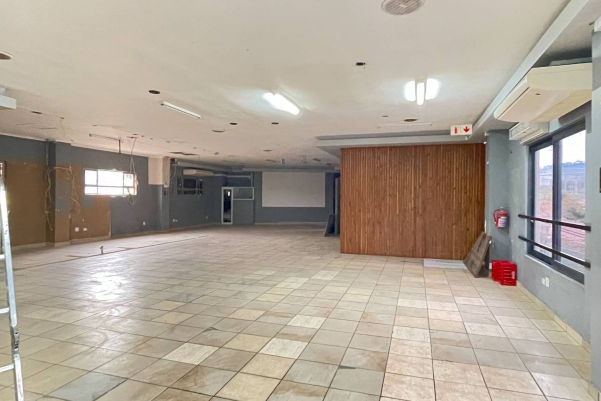 Spacious open-plan industrial area featuring tiled flooring, wood paneling, and wall-mounted air conditioning, suitable for a variety of commercial or office configurations.