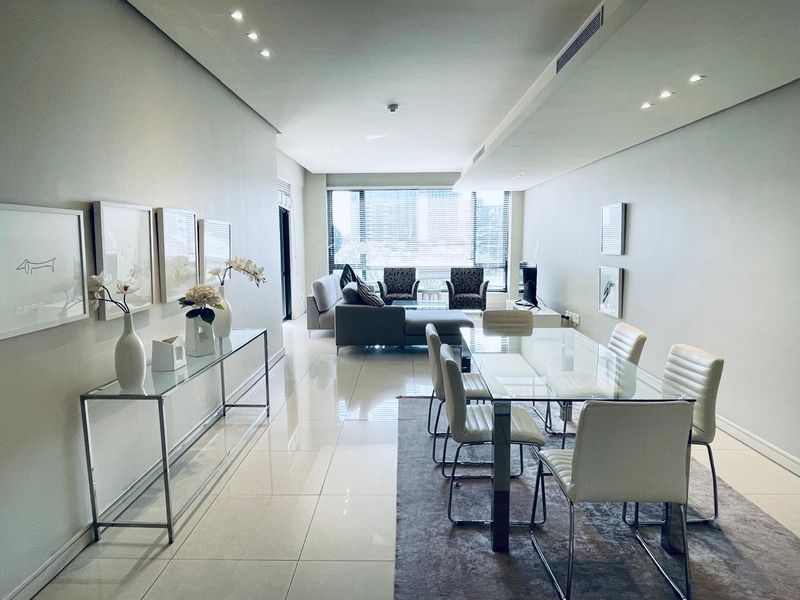 Spacious open-plan living and dining area featuring polished porcelain tiles, recessed lighting, ducted air conditioning, and large windows providing ample natural light.