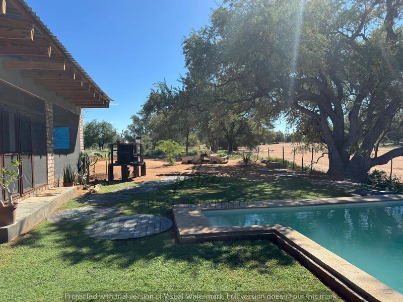 Outdoor pool area featuring a swimming pool with stone coping, adjacent to a covered patio with exposed timber rafters and brick wall construction.