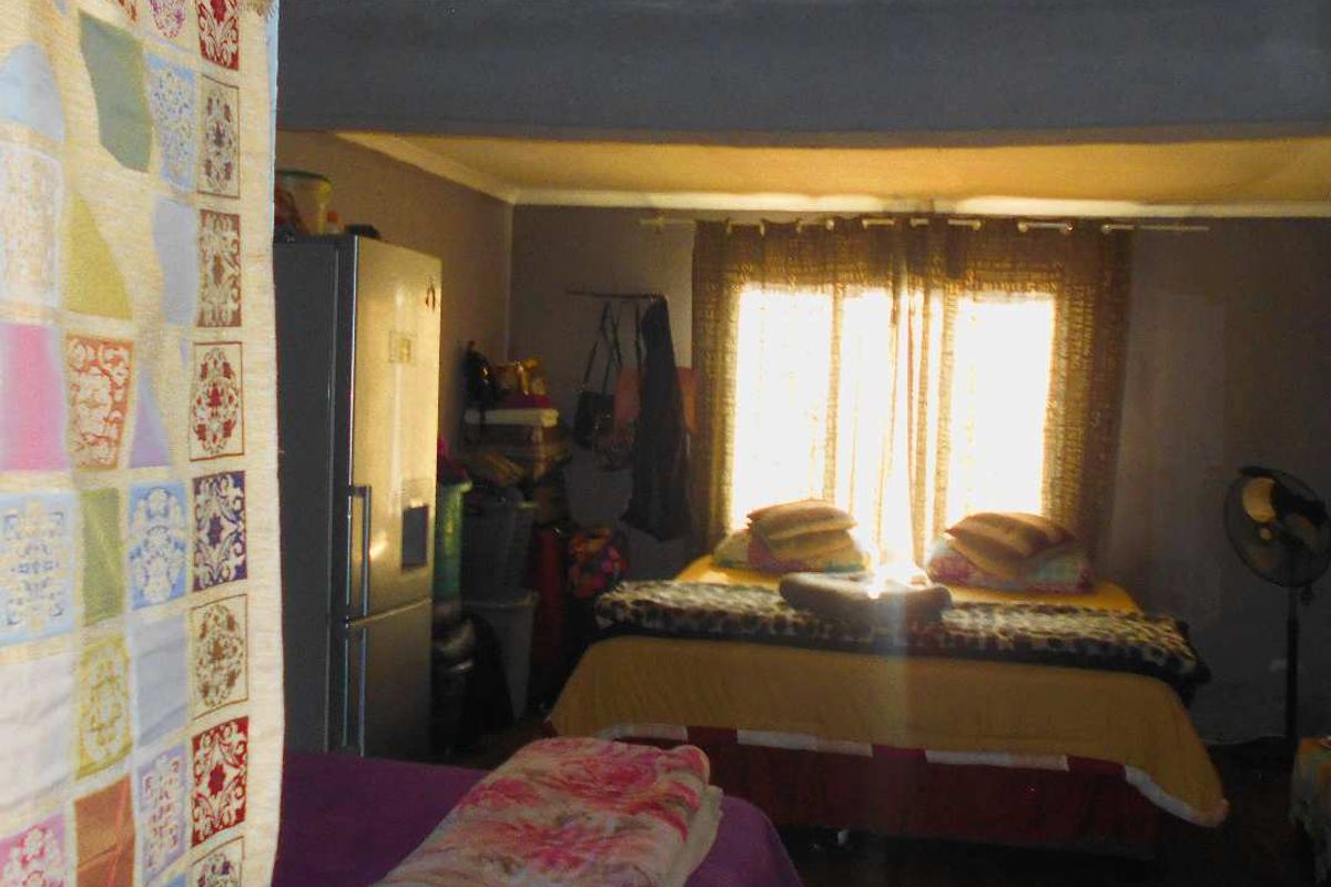 A bedroom space featuring a window with curtain rails and basic interior finishes.