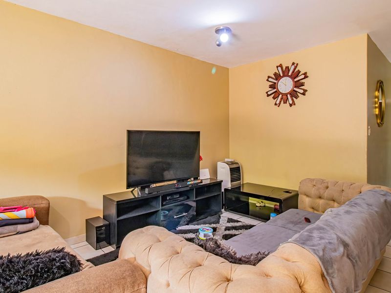A living room area featuring tiled flooring and neutral wall paint, providing a functional space for relaxation and entertainment.