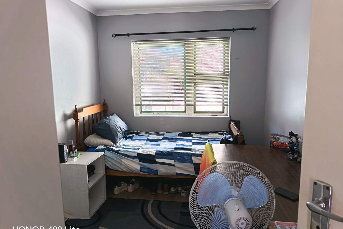 A standard bedroom featuring a window with fitted blinds and neutral wall finishes.