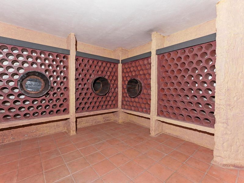 A dedicated wine cellar featuring built-in terracotta bottle storage racks and durable terracotta floor tiling.