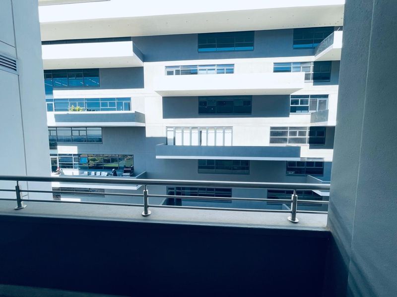 A view from a balcony overlooking the modern architectural facade of the apartment complex, featuring clean lines and stainless steel balustrades.
