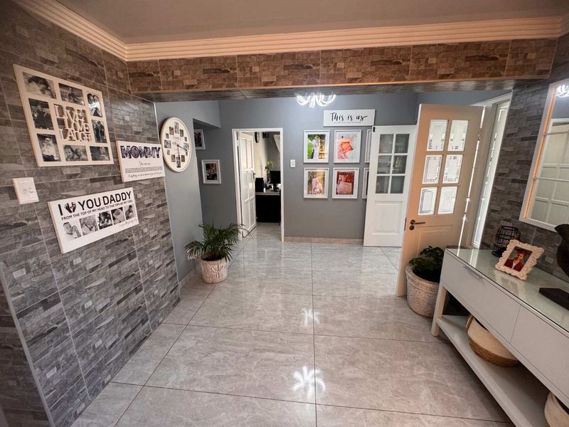 A well-maintained hallway featuring polished floor tiles, a decorative stone-cladding feature wall, and elegant crown molding, providing a bright and welcoming entrance.
