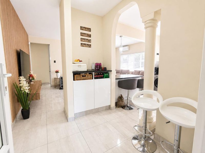 Open plan living area featuring tiled floors, a decorative archway with column, and integrated cabinetry, creating a seamless flow between the living and kitchen spaces.