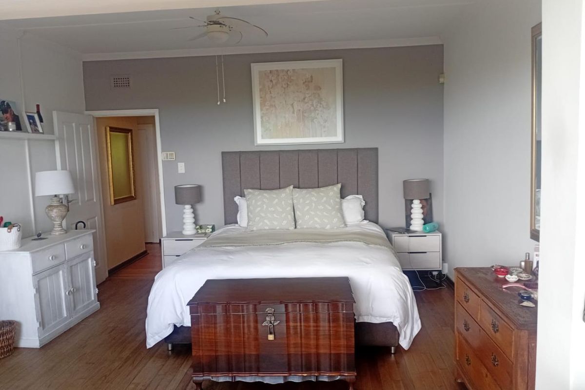 A well-proportioned bedroom featuring timber flooring, a ceiling fan, and neutral wall tones, providing a comfortable and functional living space.