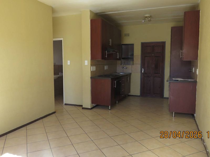 Open-plan kitchen and living area featuring tiled flooring, dark wood cabinetry, and a built-in hob with extractor fan.
