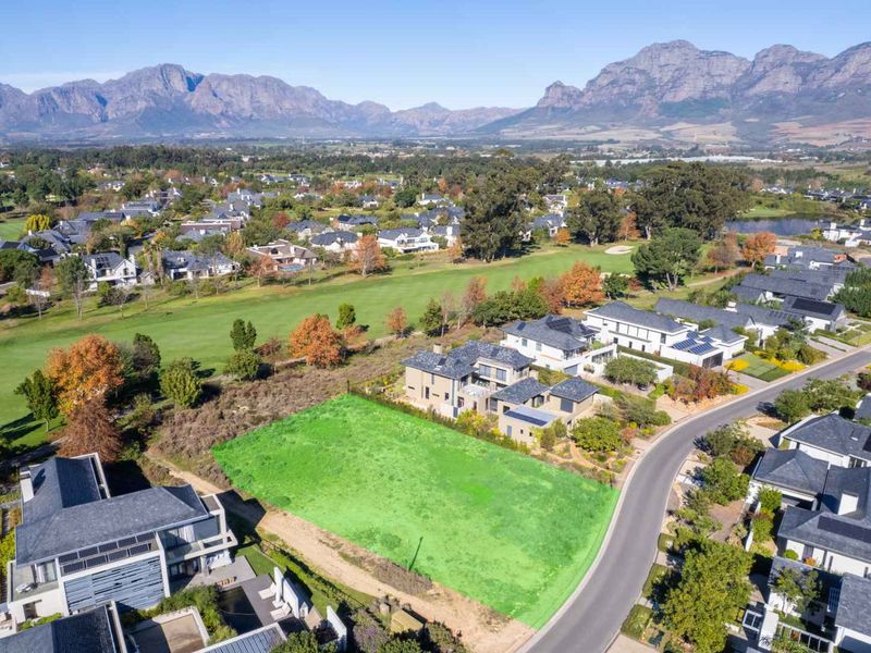 Aerial view of a vacant residential plot situated in a premium estate, featuring scenic mountain views and proximity to a golf course.