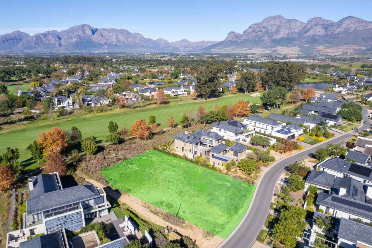 Aerial view of a vacant residential plot situated in a premium estate, featuring scenic mountain views and proximity to a golf course.