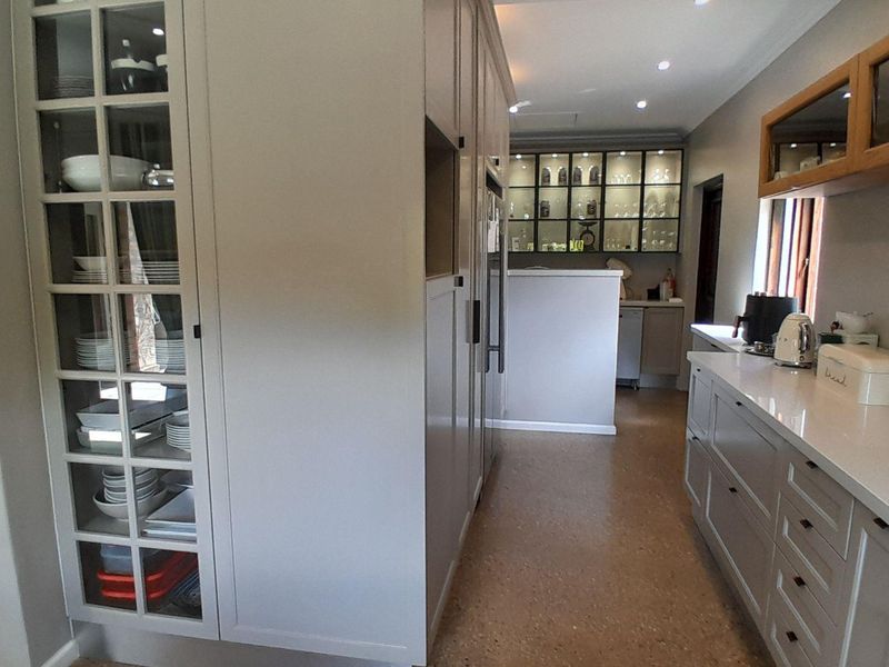 Modern kitchen featuring high-quality built-in cabinetry, glass-fronted display units, stone countertops, and durable terrazzo flooring with recessed lighting.
