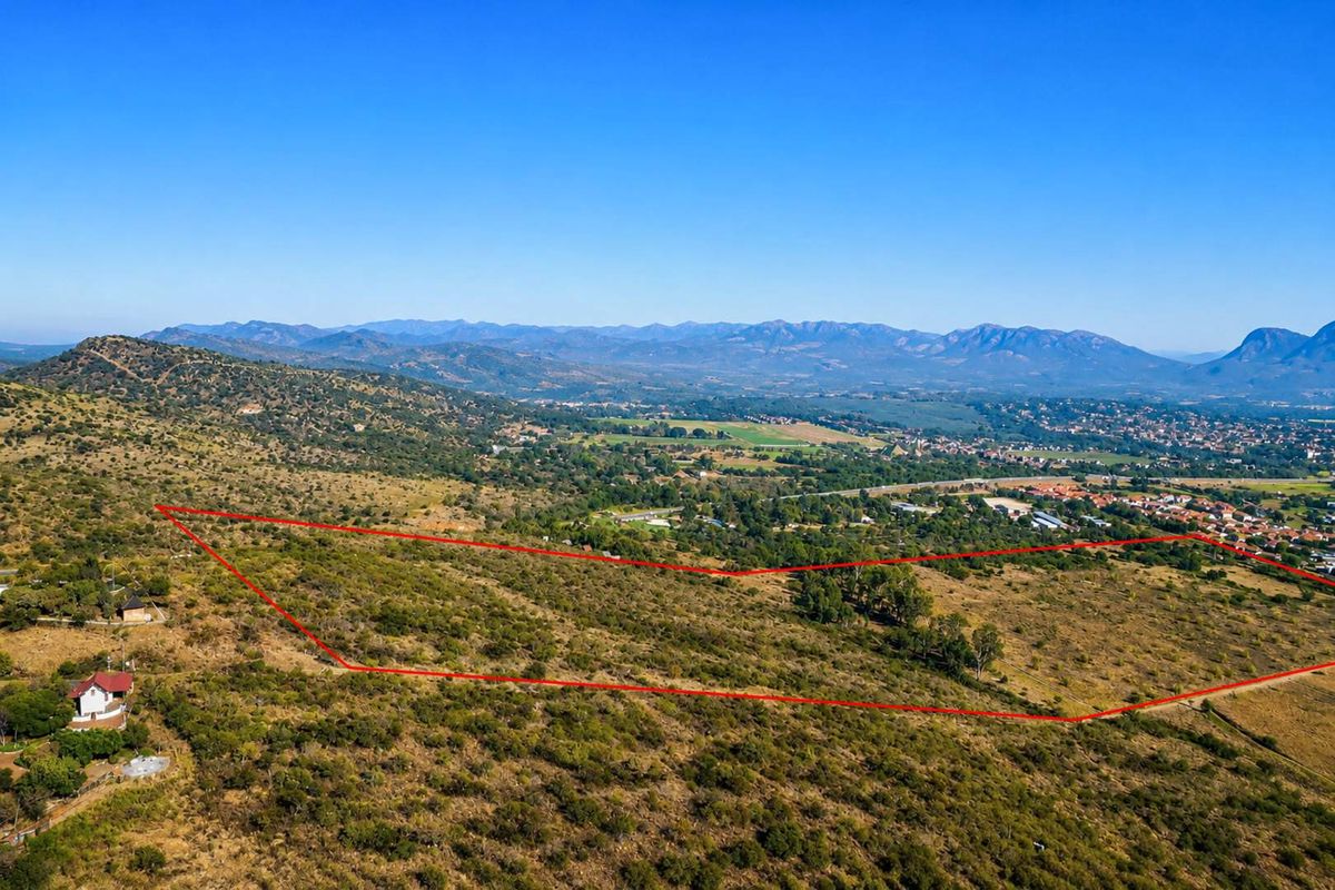 Aerial view of a large, undeveloped farm plot featuring natural landscape, rolling hills, and expansive mountain views in the distance.