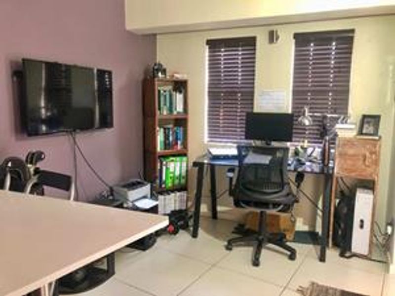A functional home office space featuring tiled flooring and venetian blinds, providing a practical area for work or study.