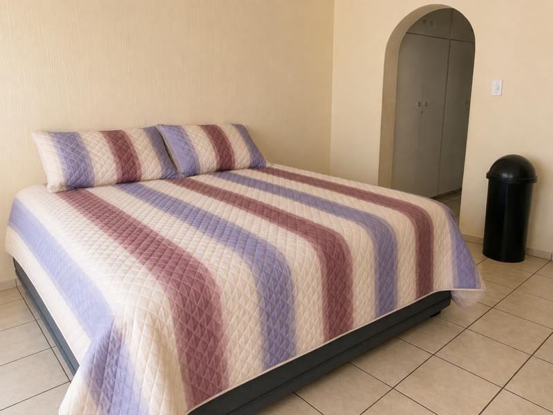 A bedroom featuring tiled flooring, neutral walls, and an arched entryway leading to built-in cupboards.