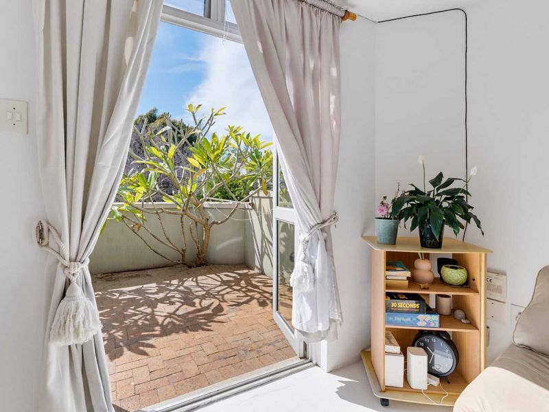 A bright balcony featuring brick paving and a clear view, accessible through a sliding glass door from the interior living space.