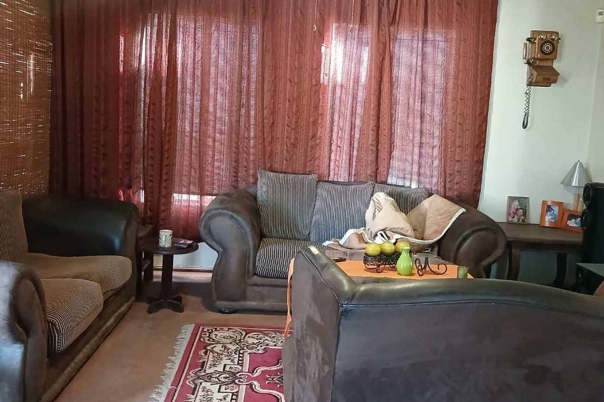 A comfortable living room featuring carpeted flooring and large window treatments, providing a functional and inviting space for relaxation.