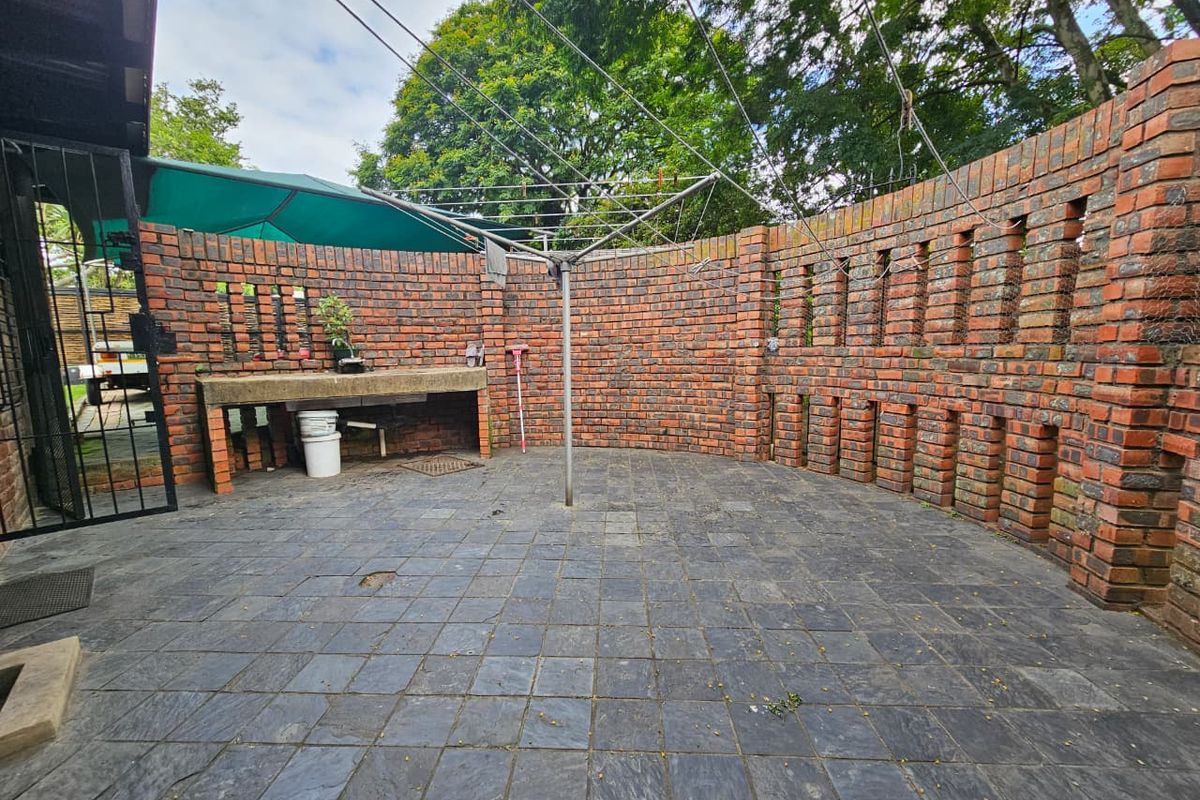 A private outdoor courtyard featuring a curved face-brick boundary wall, slate-tiled flooring, and a built-in concrete prep counter.