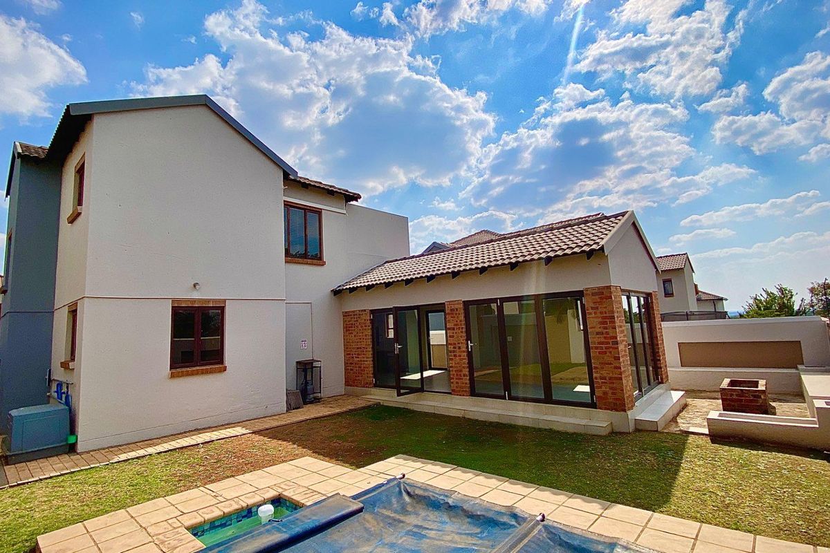 Rear view of the townhouse featuring a private garden, swimming pool, paved patio area, and a sunroom with large glass sliding doors.