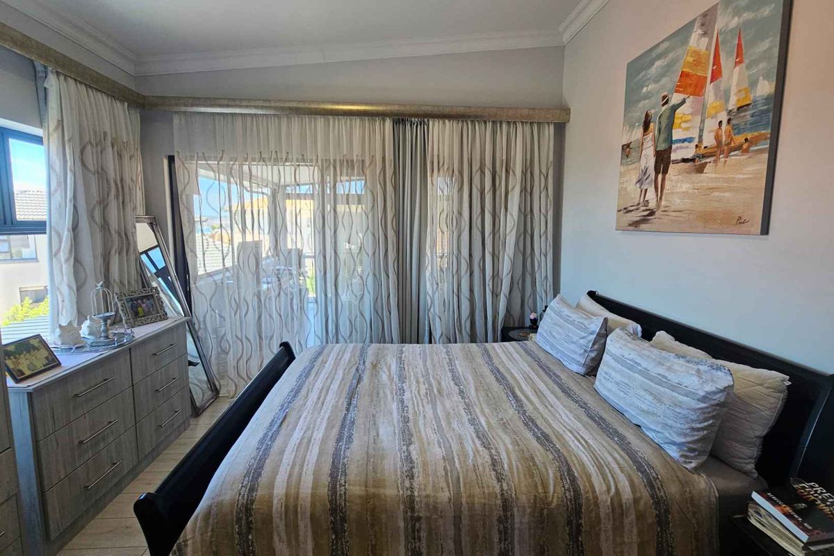 A well-maintained bedroom featuring built-in cabinetry, tiled flooring, and large sliding glass doors that provide access to an adjoining balcony.