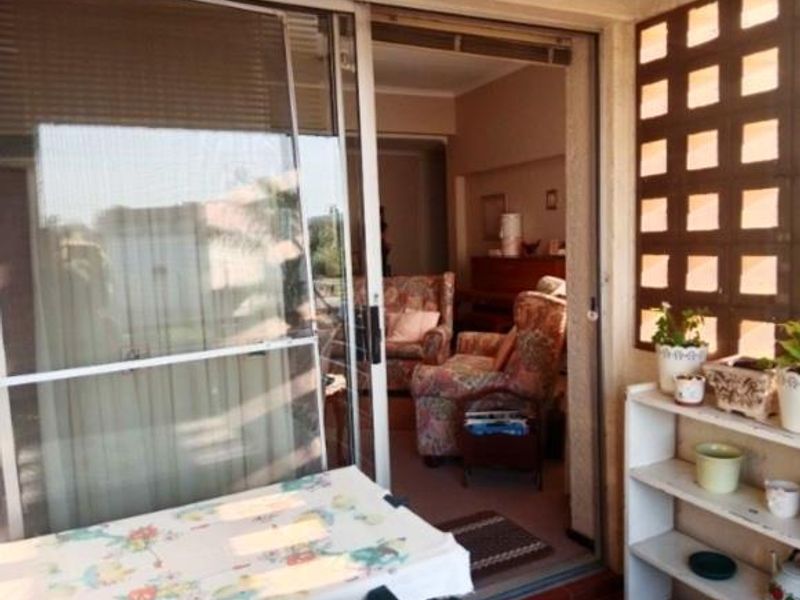A covered balcony area featuring a decorative breeze block screen and sliding glass door access to the interior living space.
