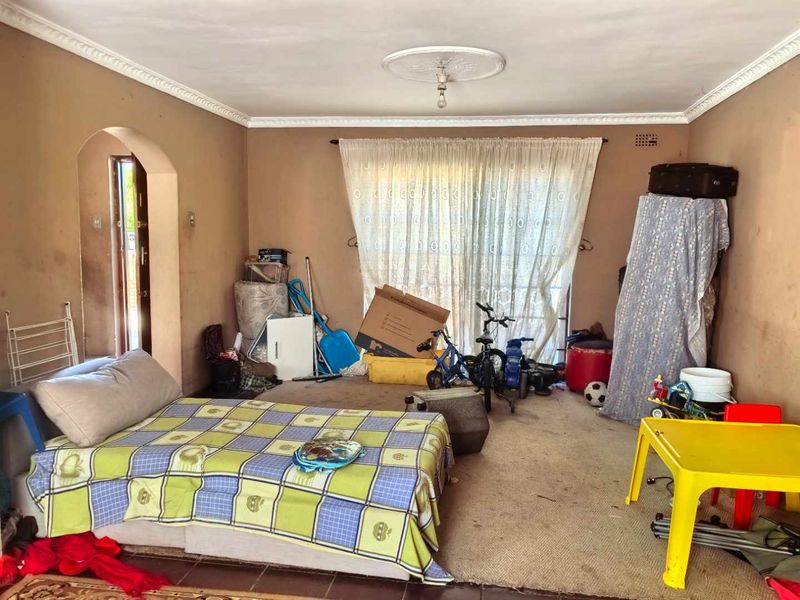 A living room space featuring coving, a ceiling rose, and sliding glass doors leading to the exterior, currently requiring significant cosmetic updates and repairs.