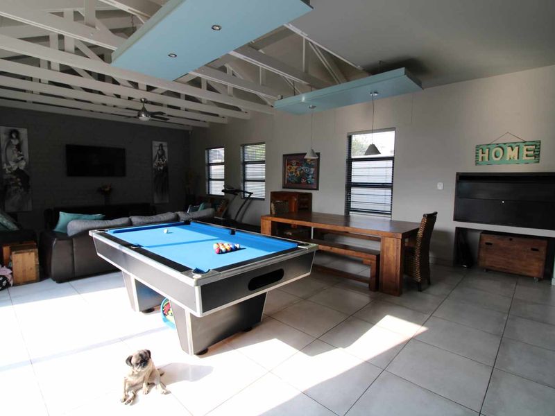 Spacious living area featuring exposed timber roof trusses, tiled flooring, and a built-in fireplace, offering a versatile space for relaxation and entertainment.