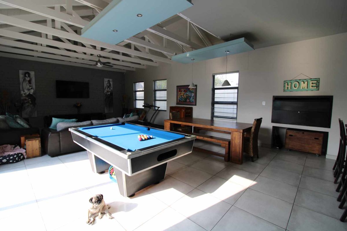 Spacious living area featuring exposed timber roof trusses, tiled flooring, and a built-in fireplace, offering a versatile space for relaxation and entertainment.