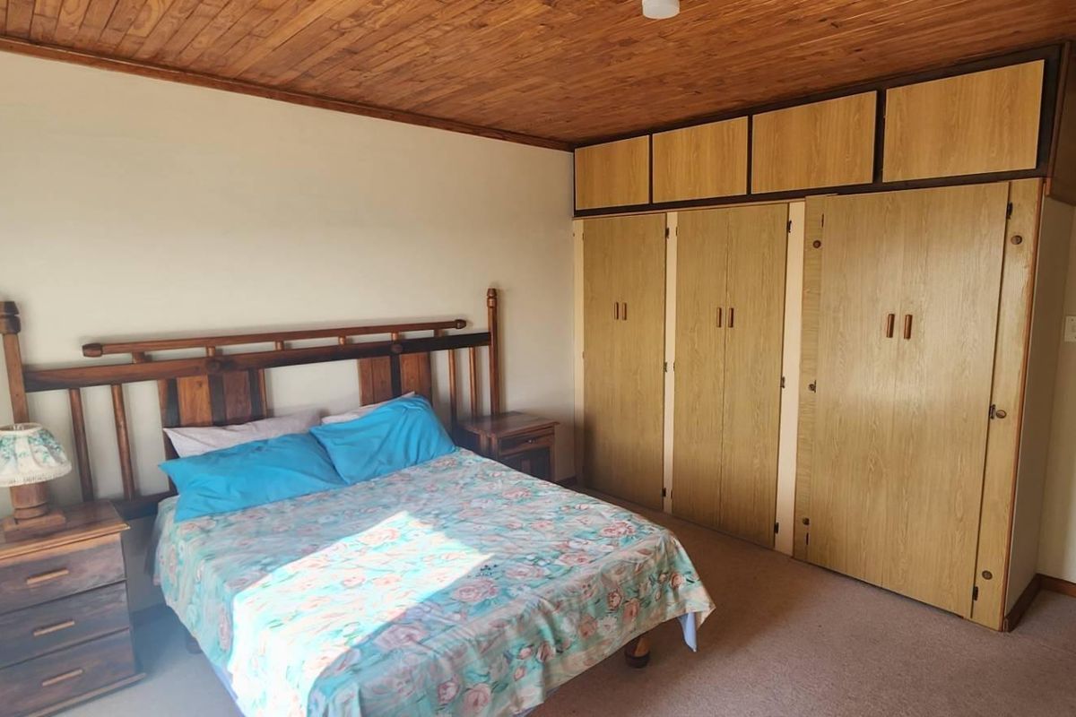 A bedroom featuring built-in wooden cupboards, a timber-clad ceiling, and carpeted flooring.