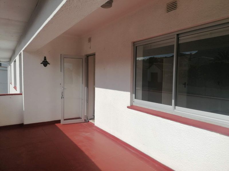 A covered balcony area featuring a painted concrete floor, aluminium sliding window, and access door, providing a functional outdoor space.