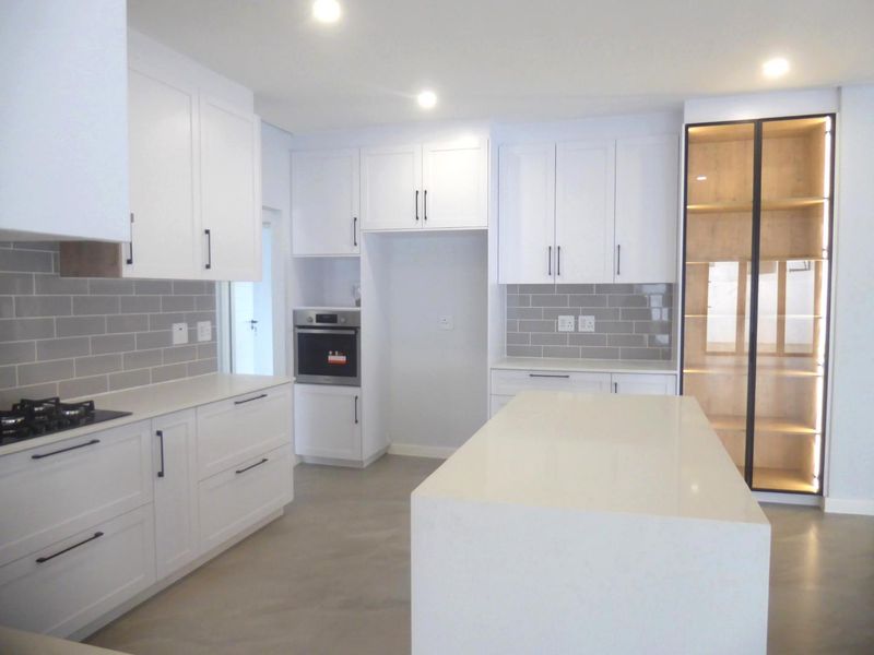 Modern kitchen featuring white cabinetry, quartz countertops, a central island, built-in oven, gas hob, and stylish subway tile backsplash.