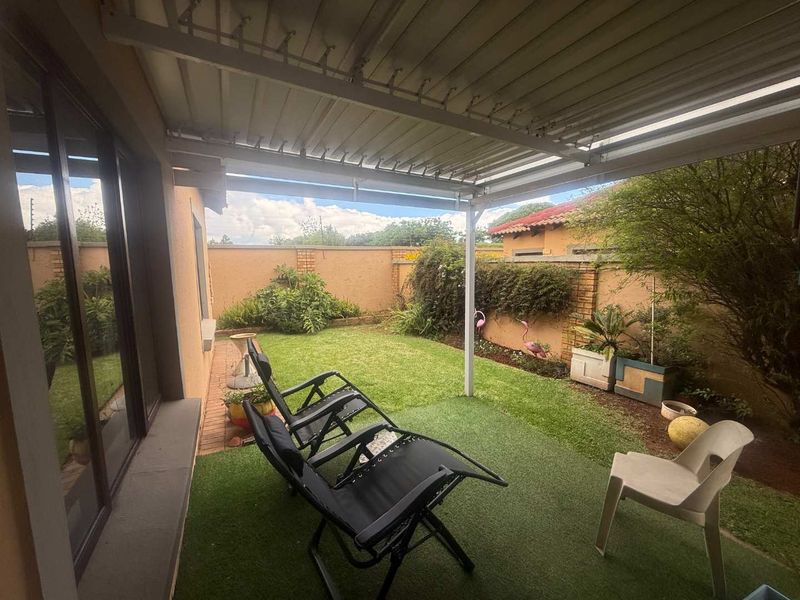 A covered patio area featuring artificial grass flooring, providing a seamless transition to the private rear garden and boundary wall.