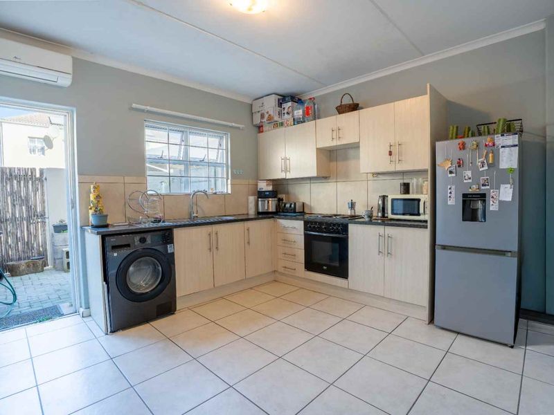 Functional kitchen featuring light wood cabinetry, tiled flooring, built-in oven and hob, and direct access to an outdoor patio area.