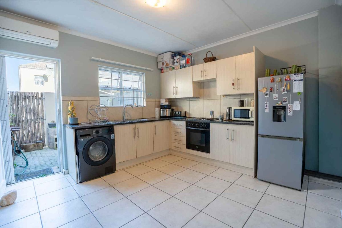 Functional kitchen featuring light wood cabinetry, tiled flooring, built-in oven and hob, and direct access to an outdoor patio area.
