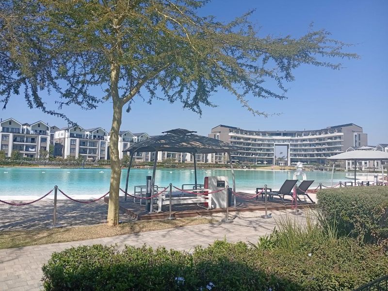 A well-maintained communal pool area featuring a large swimming pool, cabana, and landscaped surroundings within a modern apartment complex.
