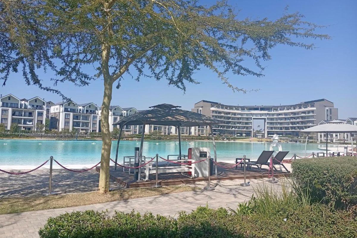 A well-maintained communal pool area featuring a large swimming pool, cabana, and landscaped surroundings within a modern apartment complex.