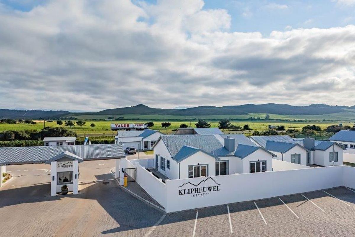 Aerial view of Klipheuwel Estate featuring a secure entrance gatehouse, paved parking area, and modern residential units with metal roofing.