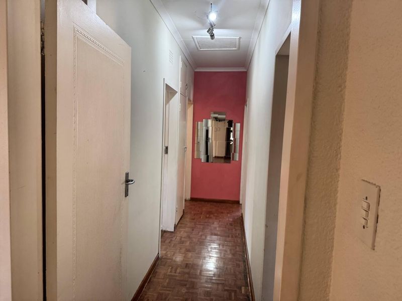 A functional hallway featuring classic parquet flooring, built-in storage cupboards, and direct access to the ceiling space.
