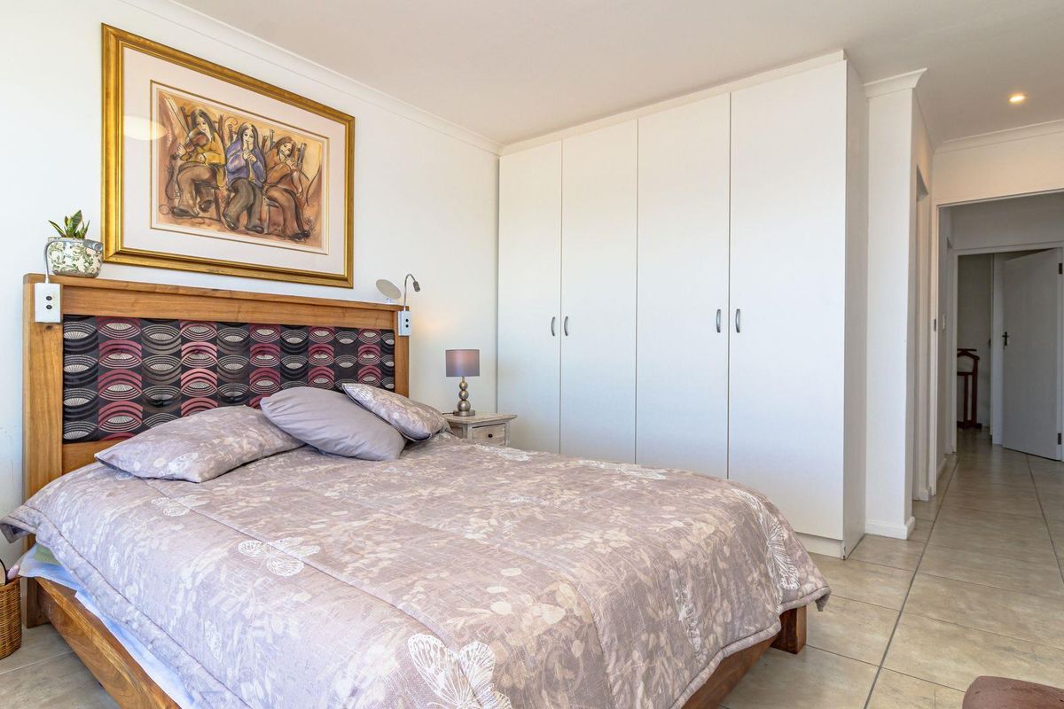 A well-maintained bedroom featuring built-in floor-to-ceiling wardrobes, tiled flooring, and neutral finishes, providing a clean and functional living space.