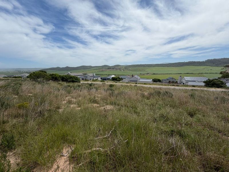 A scenic view overlooking a residential area with rolling green hills and natural landscape in the background.