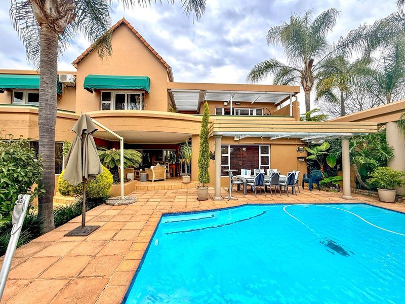 Rear exterior view featuring a swimming pool, paved patio area, and a covered pergola, providing an ideal space for outdoor entertaining.