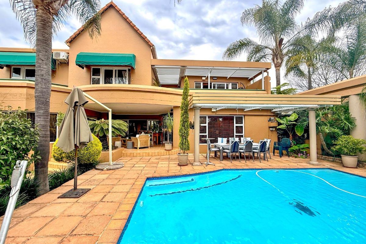 Rear exterior view featuring a swimming pool, paved patio area, and a covered pergola, providing an ideal space for outdoor entertaining.