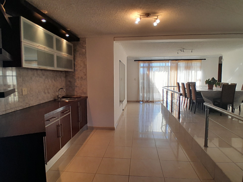Open-plan living and dining area featuring tiled floors, a functional kitchen with built-in cabinetry, and access to a bright, naturally lit space.