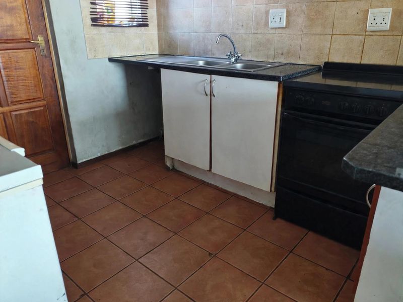 A functional kitchen featuring tiled flooring, granite countertops, a double sink, and a built-in oven with tiled backsplash.