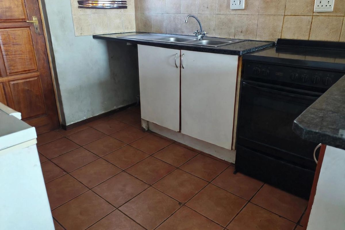 A functional kitchen featuring tiled flooring, granite countertops, a double sink, and a built-in oven with tiled backsplash.